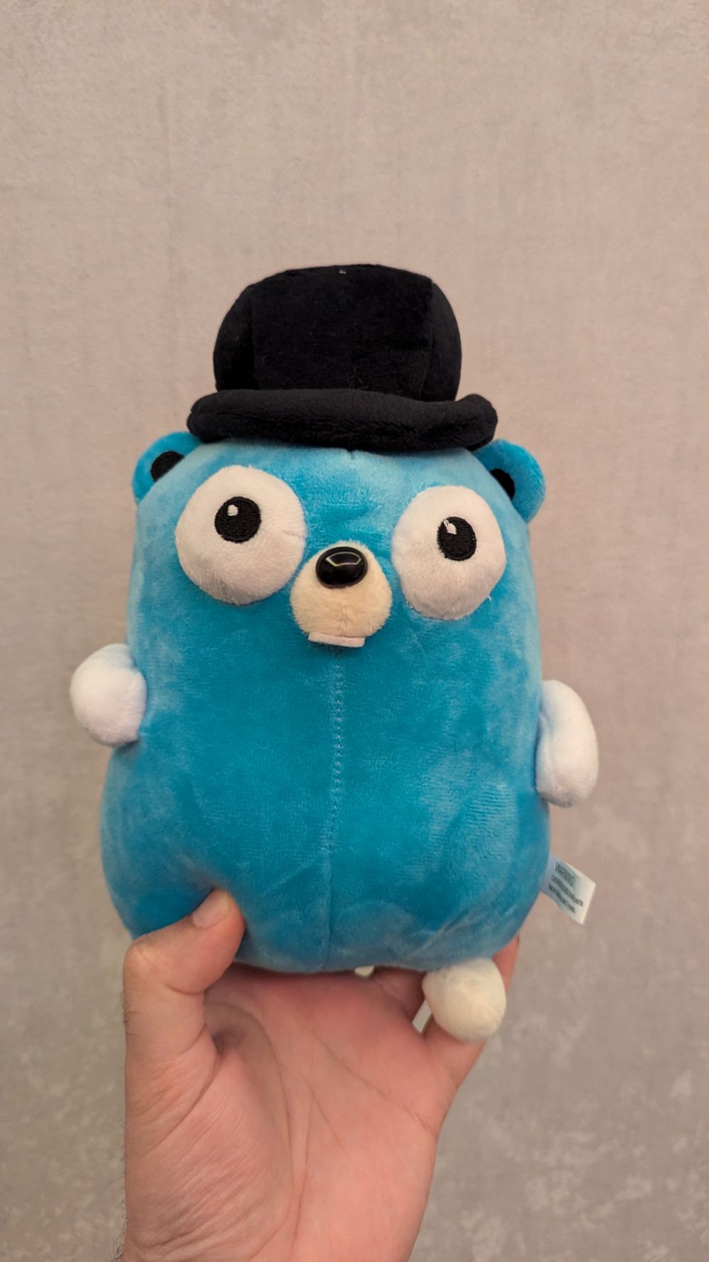 A Gopher plushie (the gopher being the Go programming language's official mascot) with a little bowler hat, following the GopherConUK branding