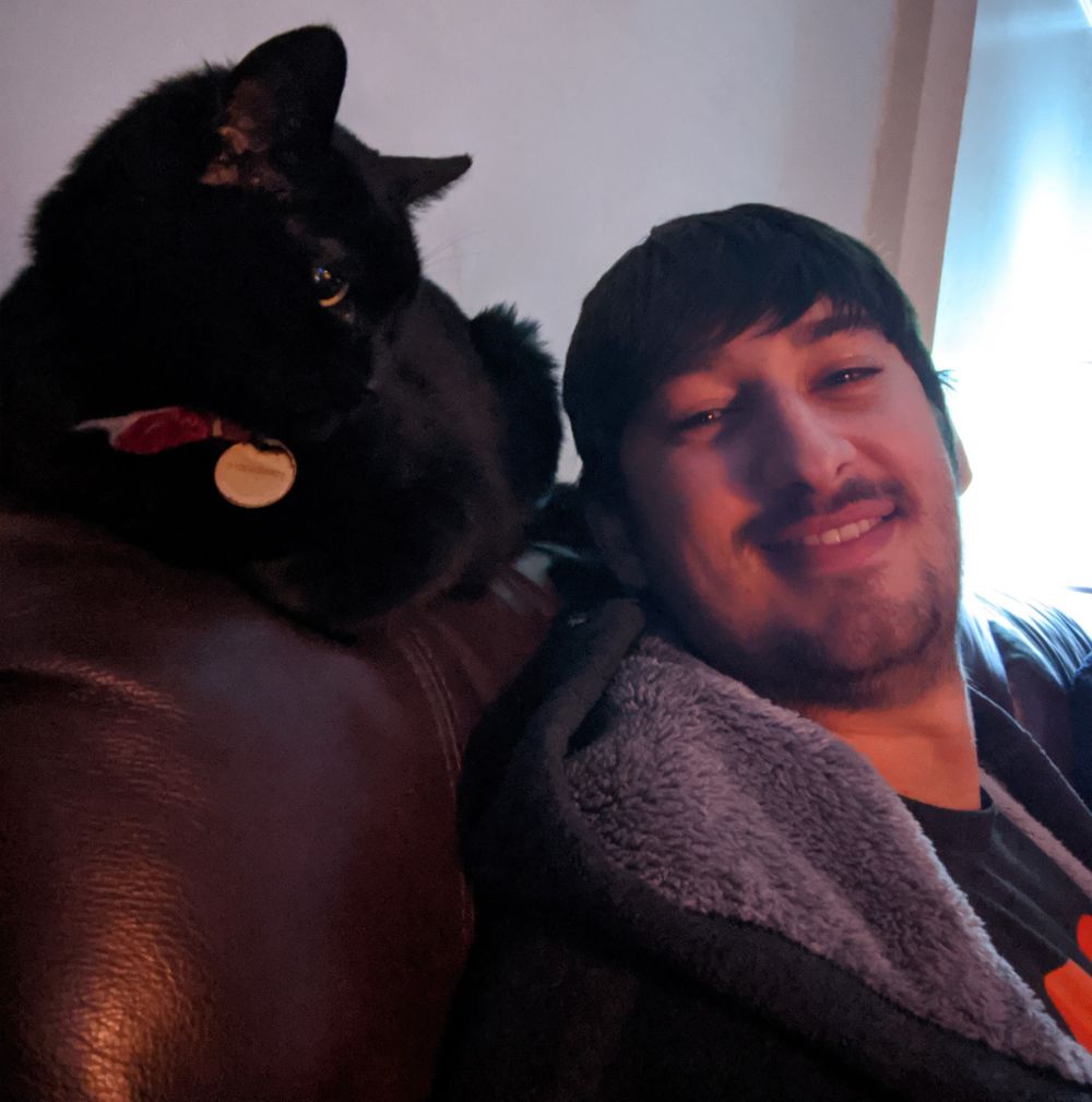Black cat sitting on back of the sofa behind Jamie, like a parrot