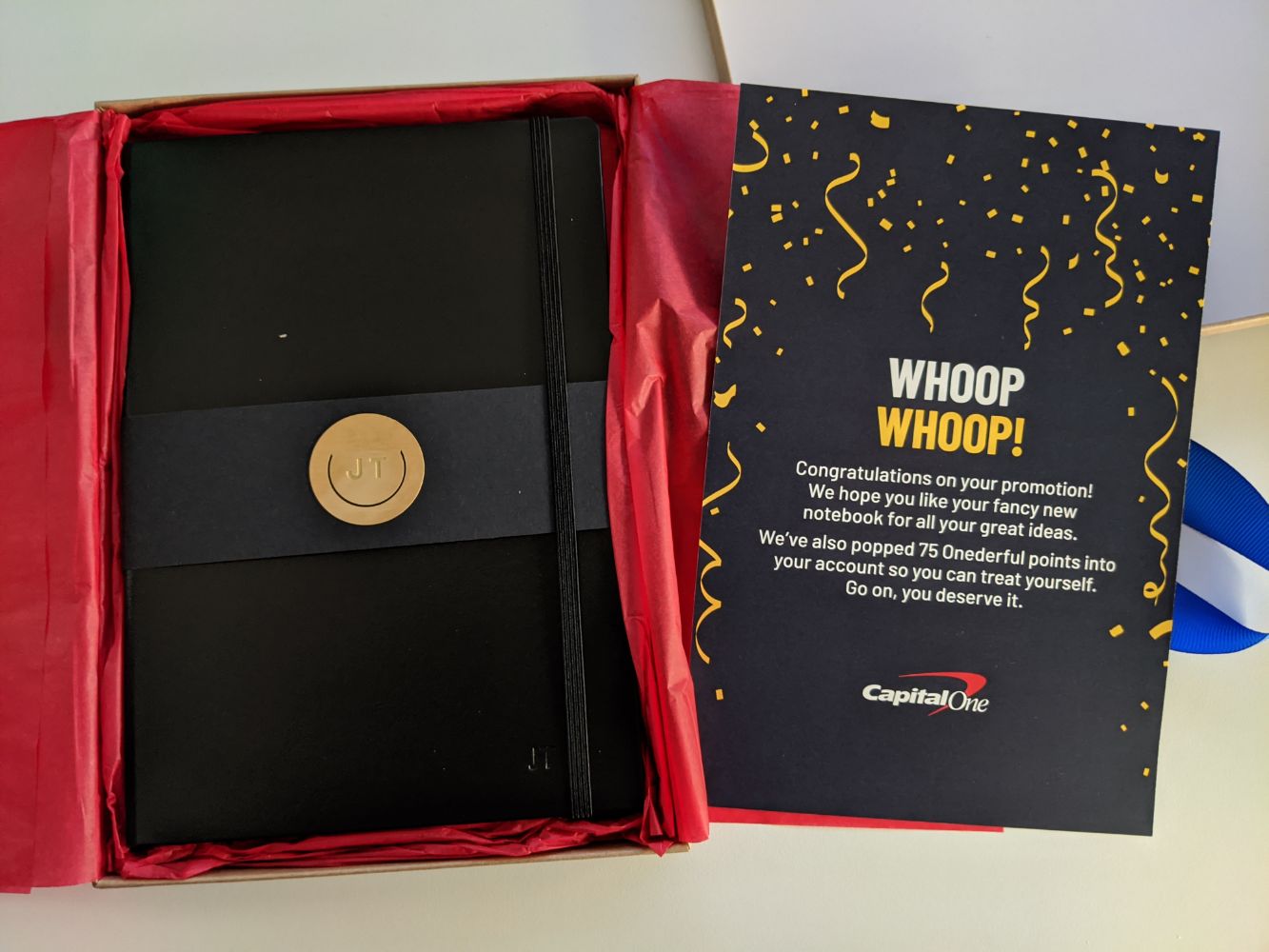 The inside of the parcel - on the right, a card with a congratulatory message inside it. On the left, a black notebook, embossed with Jamie's initials