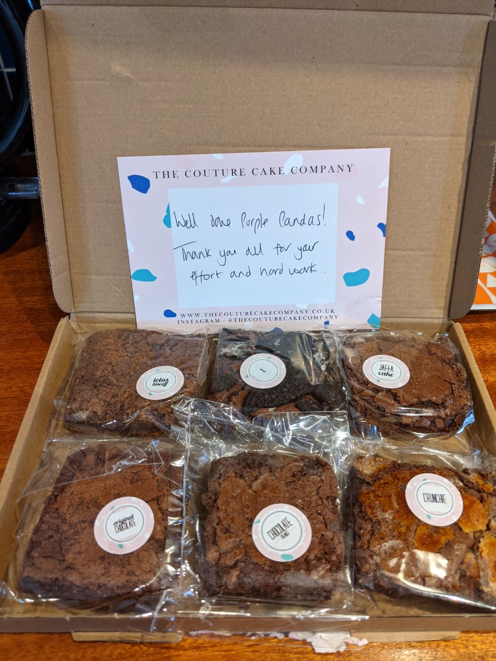 A package from the Couture Cake Company containing 6 brownies - Lotus Biscoff, Oreo, Jaffa Cake, Chocolate, Chocolate Orange and Crunchie - with a note saying "Well done Purple Pandas (our team name)! Thank you for all your effort and hard work"