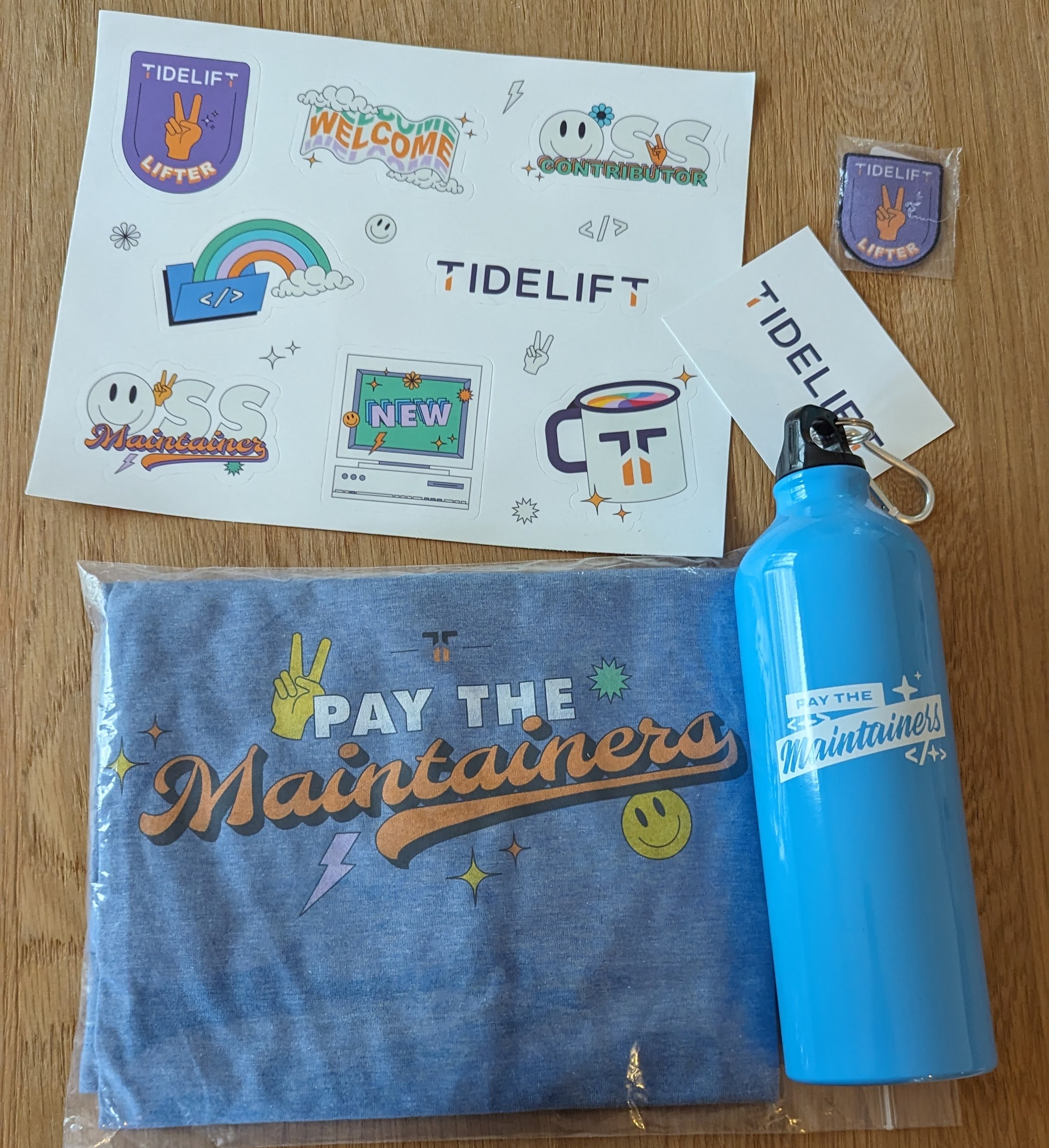 A t-shirt with "pay the maintainers", some cute emoji and the Tidelift logo, a "pay the maintainers" water bottle, a "Tidelift lifter" patch to sew onto i.e. a jacket, and a book of various Tidelift stickers, which all look really great!