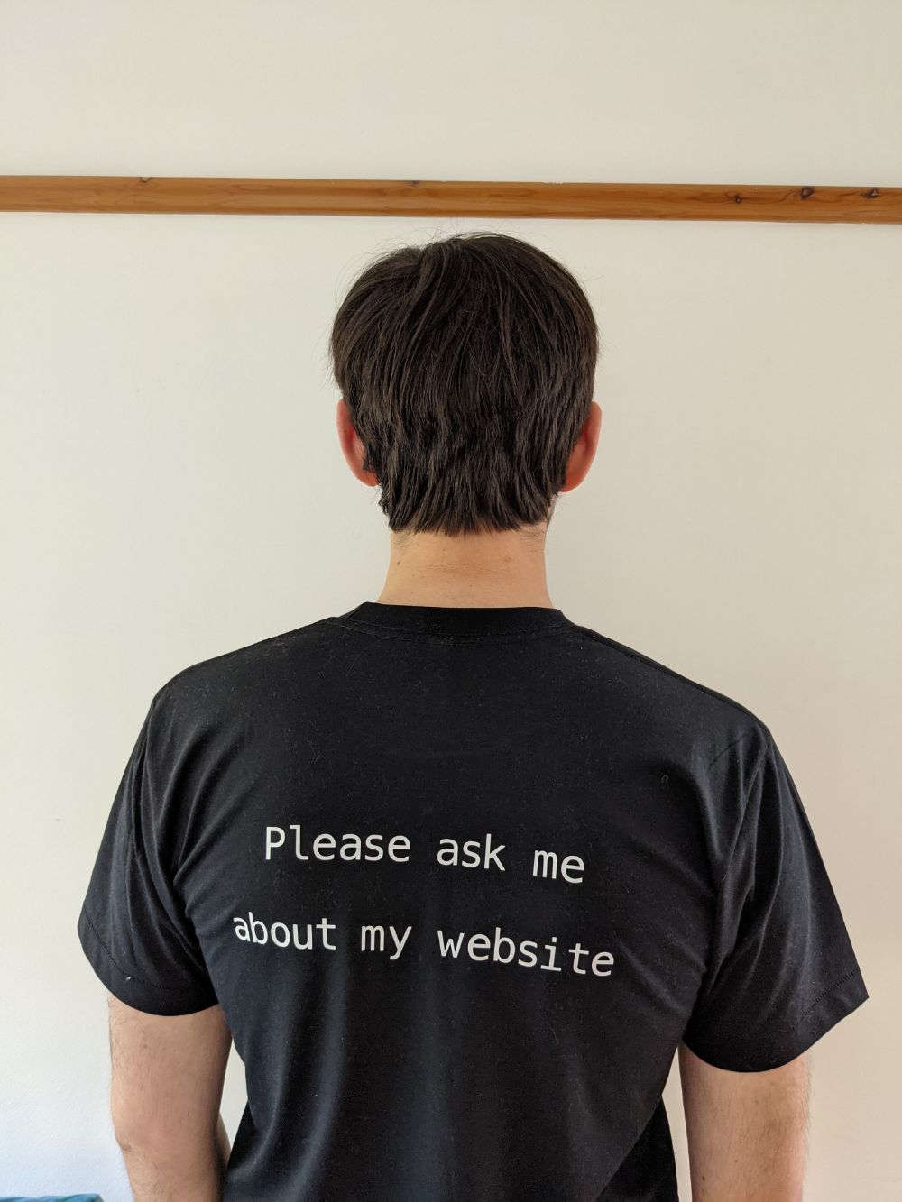 Jamie facing away from the camera with "Please ask me about my website" written on the back of the t-shirt