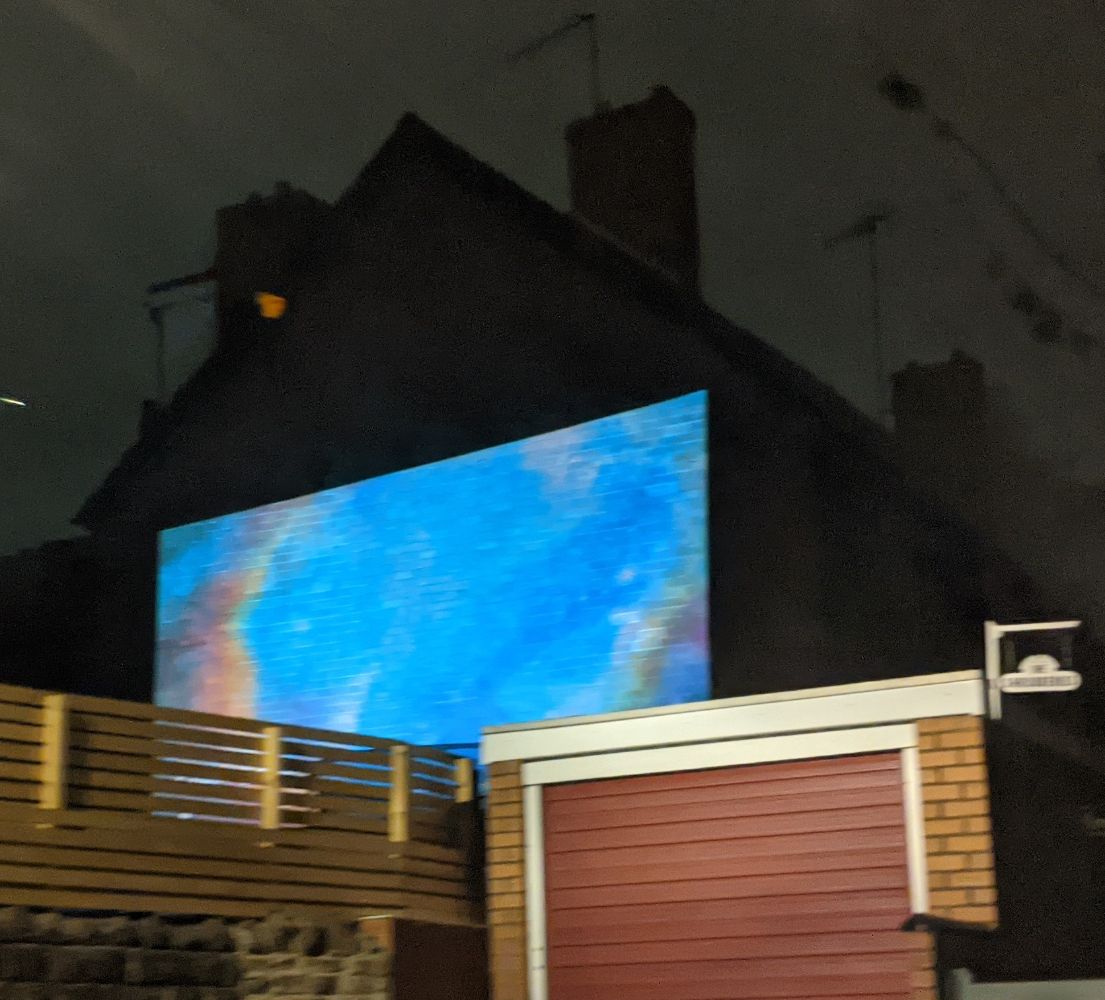 A projector using the side of the house to create a huge outside screen