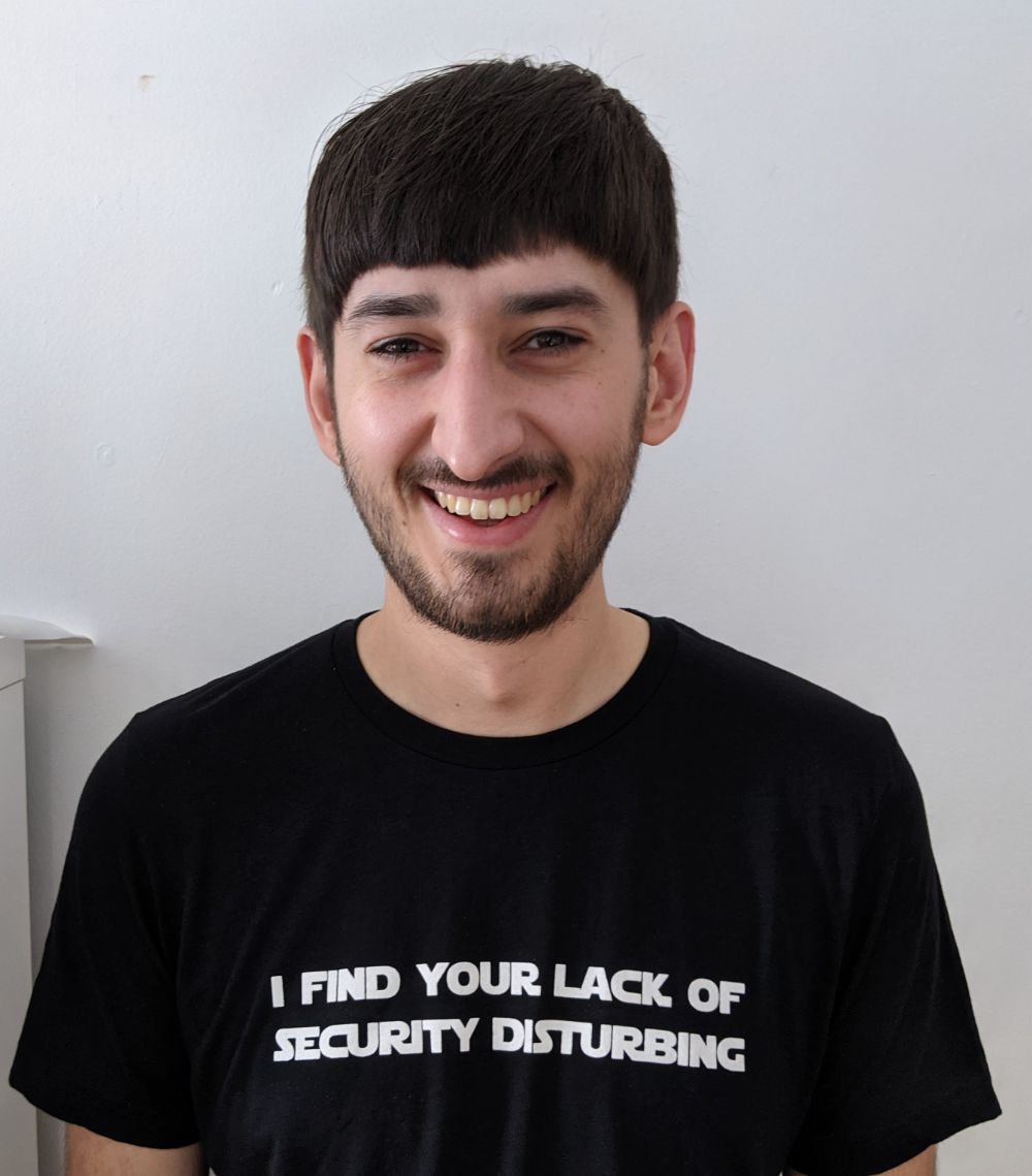 Photo of Jamie smiling at the camera with a t-shirt with the text "I find your lack of security disturbing"