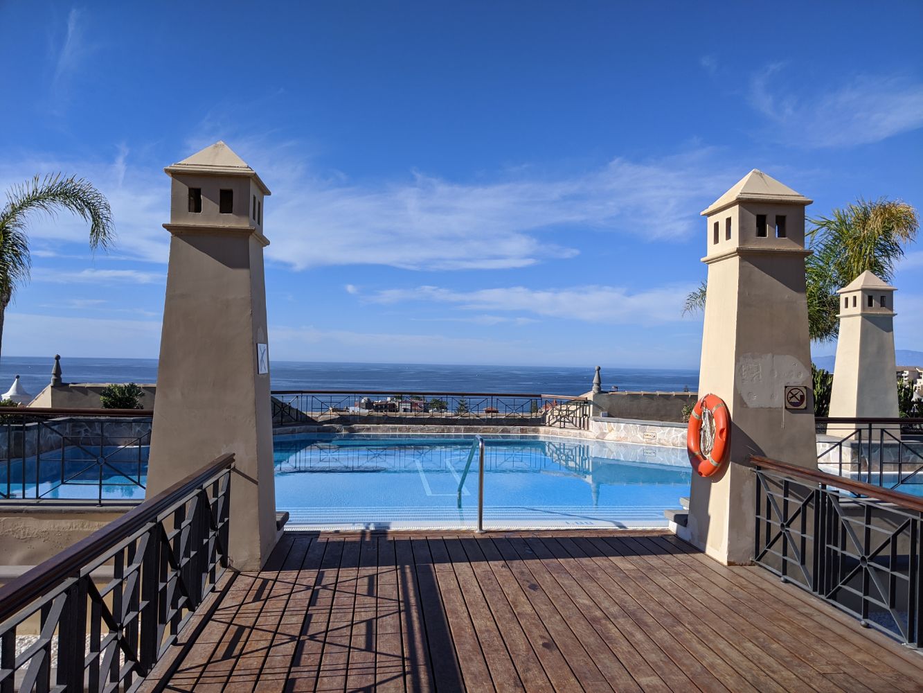 A pool on the roof, with a view out to sea and a blue sky, with some small clouds