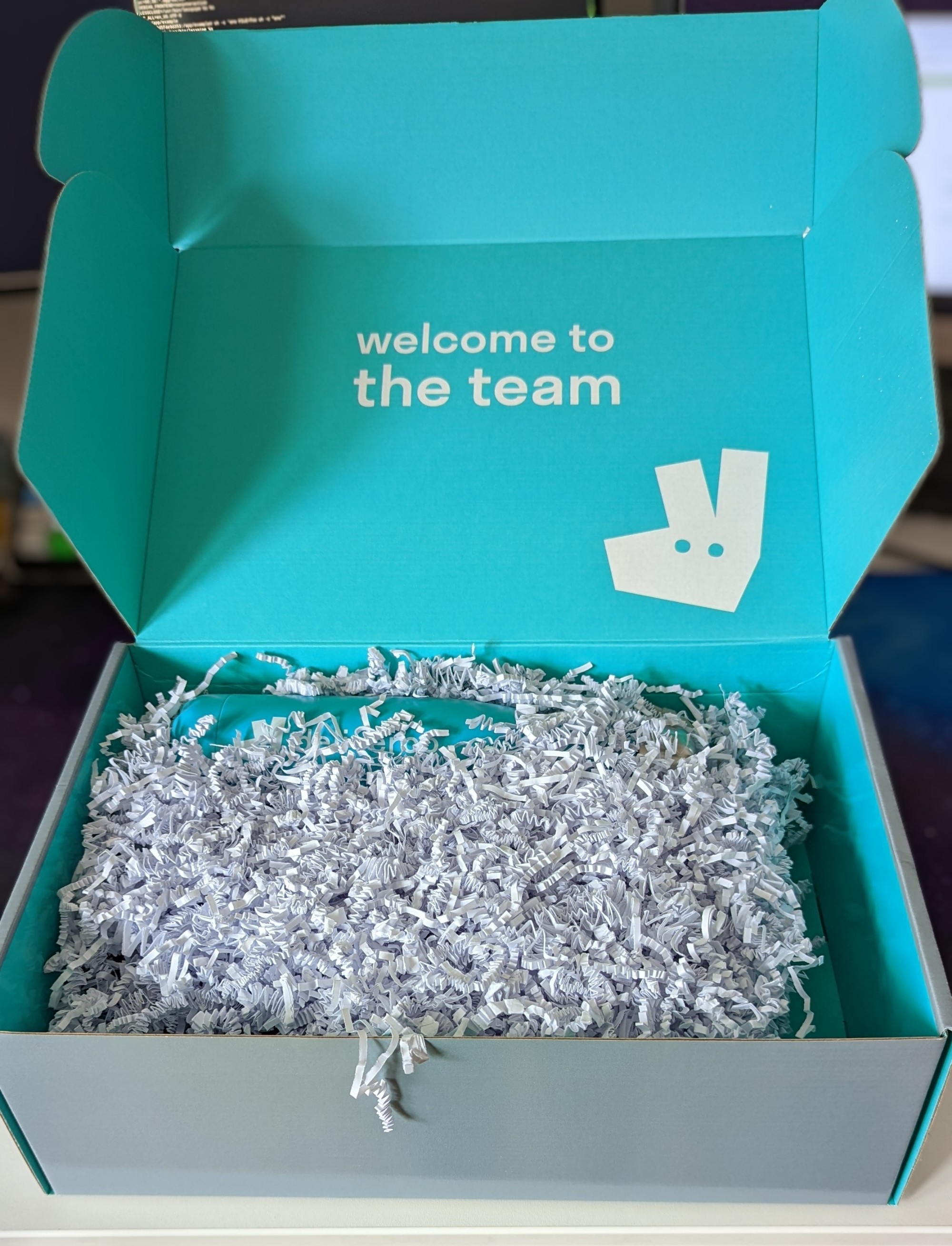 The box opened up, with "welcome to the team" on the inside lid, and swag inside covered with tasteful paper packing material. The inside of the box is Deliveroo blue