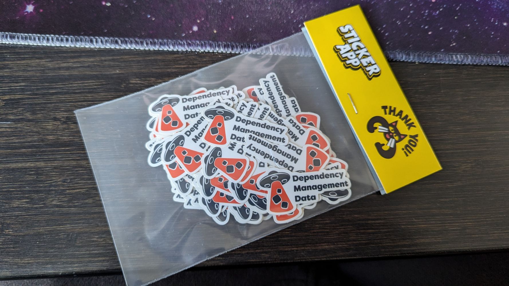 A packet of ~30 stickers from Sticker App, showing the Dependency Management Data UFO and text, which look pretty cool and you definitely want one