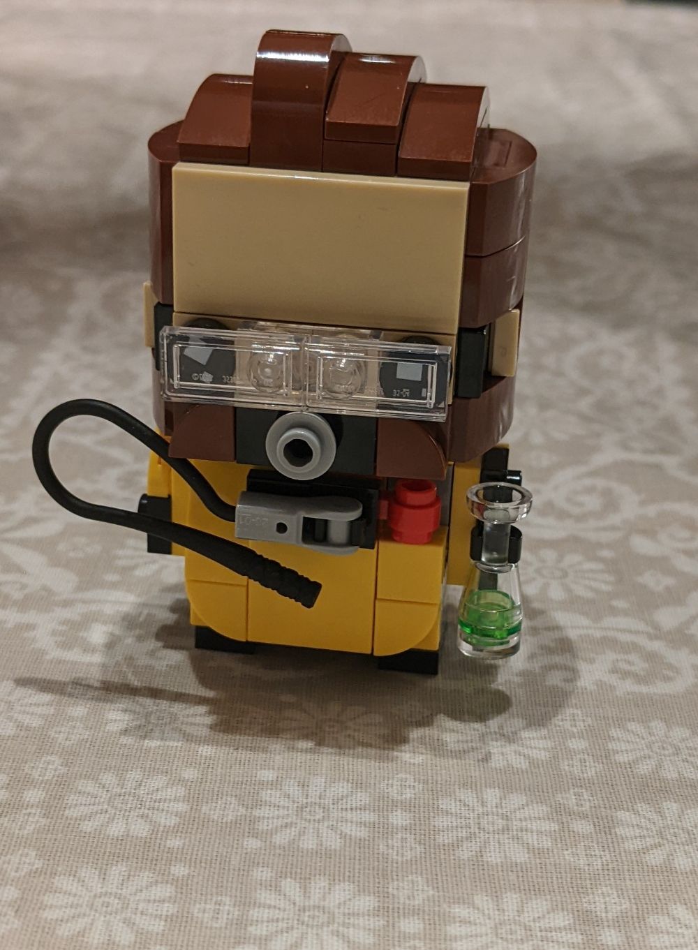A Lego Brickheadz figure of the Apex Legends character Caustic - Caustic is holding a vial that is radioactive green