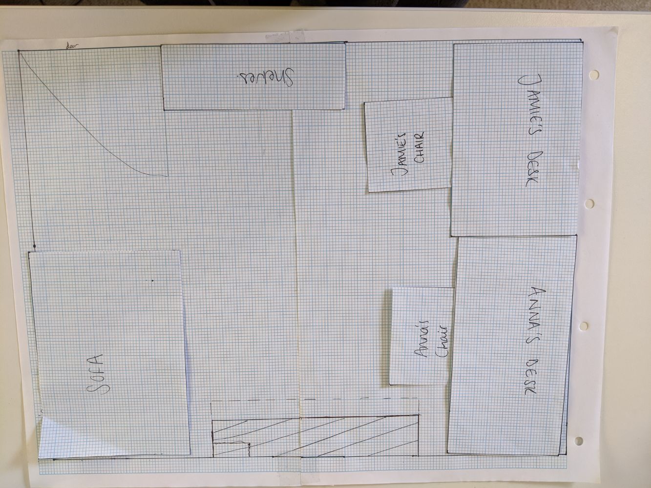 Floor plan of Jamie and Anna's desks right next to each other on one side of the room, with shelves behind Jamie and a sofa in the window