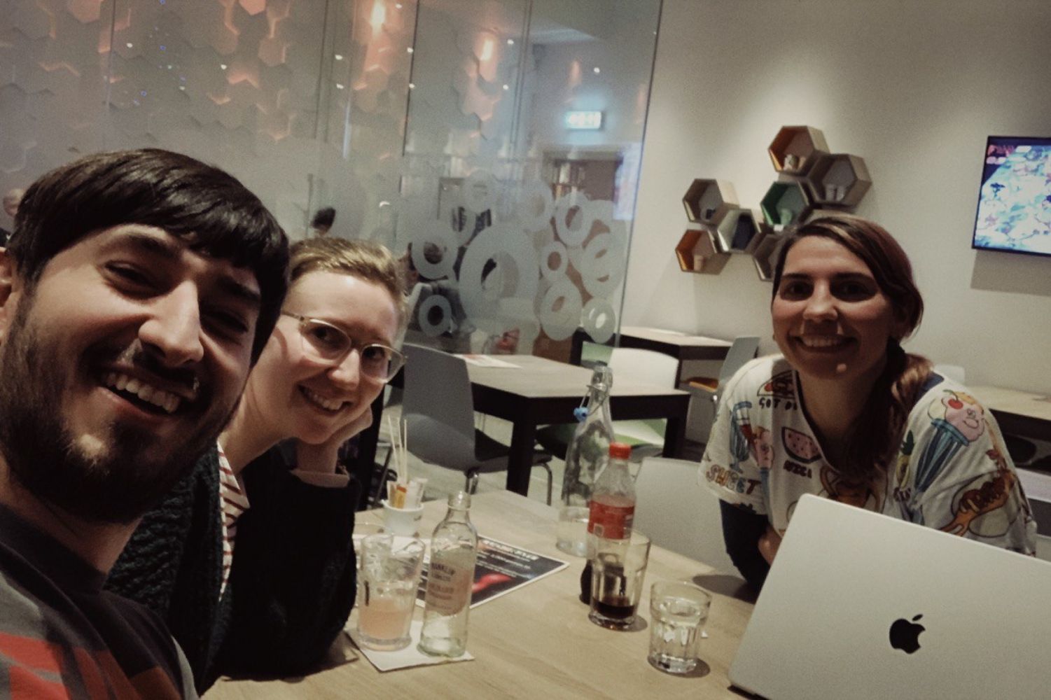Photo of Jamie, Anna and Carol in person at Ludorati board game cafe, smiling at the camera