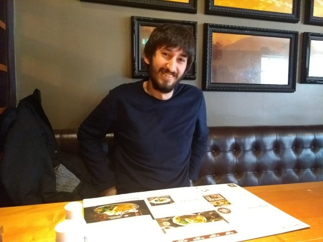 Jamie looking gaunt, with long hair and a beard, in a pub, mostly smiling